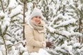 Beautiful woman standing among snowy trees in winter forest and enjoying first snow. Woman in winter woods. Royalty Free Stock Photo