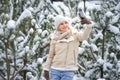 Beautiful woman standing among snowy trees in winter forest and enjoying first snow. Woman in winter woods. Royalty Free Stock Photo