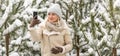 Beautiful woman standing among snowy trees in winter forest and enjoying first snow. Woman in winter woods. Royalty Free Stock Photo