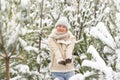 Beautiful woman standing among snowy trees in winter forest and enjoying first snow. Woman in winter woods. Royalty Free Stock Photo