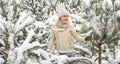 Beautiful woman standing among snowy trees in winter forest and enjoying first snow. Woman in winter woods. Royalty Free Stock Photo