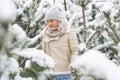 Beautiful woman standing among snowy trees in winter forest and enjoying first snow. Woman in winter woods. Royalty Free Stock Photo