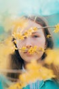 A young woman standing in the sunshine amidst yellow delicate flowers. Beauty, nature, and the joy of spring. The vibrant colors