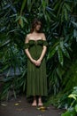 Beautiful woman standing on walking trail in jungle. Caucasian woman wearing long green dress. Bamboo leaves in tropical rain Royalty Free Stock Photo