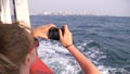 A beautiful woman stands at the stern of the ship and makes a video on the camera. Waves in the background Royalty Free Stock Photo