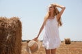 Beautiful young woman with straw hat near rolled hay bale on sunny day Royalty Free Stock Photo