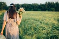 Beautiful woman with straw hat and wildflowers enjoying sunset in barley field. Atmospheric tranquil moment, slow life. Stylish Royalty Free Stock Photo
