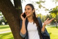 Beautiful woman student walking in park talking by mobile phone. Royalty Free Stock Photo