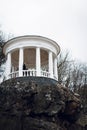 A beautiful woman with a stylish hairstyle, in a vintage black dress, sits in a white gazebo