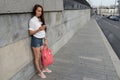 Beautiful woman in summer stands bridge, free space for copy of text, waiting for meeting and date, smartphone in hand