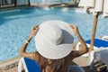 Beautiful woman sunbathing on a beach at tropical travel resort, enjoying summer holidays. Girl holding a hat with her Royalty Free Stock Photo