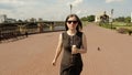 Beautiful woman in sunglasses on street walking and eating ice cream. Steadycam