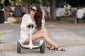 Beautiful long-haired brunette in a green park outdoors riding a segway Royalty Free Stock Photo