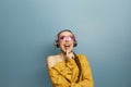 Beautiful woman with sunglasses in yellow sweater singing and having fun while listening to music using wireless earphones isolate Royalty Free Stock Photo