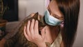 Beautiful woman in surgical face mask hugs and strokes cat