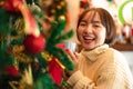 Beautiful woman in sweater is smiling and holding cup to drinking hot coffee for relax in front of christmas tree Royalty Free Stock Photo