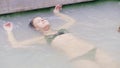Beautiful woman swimming in mineral bath from natural spring in outdoor spa. Young woman enjoying thermal bath in