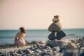 Beautiful woman in a swimsuit walking along the beach against the background of a pyramid of stones. Blurred female with stones on Royalty Free Stock Photo