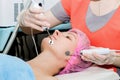 A beautiful woman takes a cosmetic procedure to improve the condition of the facial skin with microcurrents