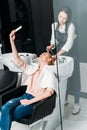 beautiful woman taking selfie while hairdresser washing her hair Royalty Free Stock Photo