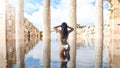 Beautiful woman taking a swim in water among ancient temple ruins