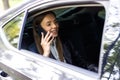 Beautiful woman is talking on the mobile phone, using a digital tablet and smiling while sitting on back seat in the car Royalty Free Stock Photo