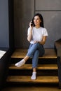 Young woman talking on the phone and working on a laptop on her lap while sitting on the stairs at home Royalty Free Stock Photo