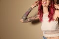 Beautiful woman with tattoos on arms against beige, closeup. Space for text