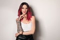 Beautiful woman with tattoos on arms against background