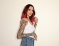 Beautiful woman with tattoos on arms against background