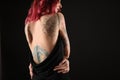 Beautiful woman with tattoos on body against background, back view. Space for text