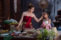 Beautiful woman teaching little girl to cooking Thai culture style. Asian woman wearing Thai dress costume traditional according Royalty Free Stock Photo