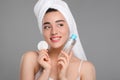 Beautiful woman in terry towel with makeup remover and cotton pad on gray background Royalty Free Stock Photo