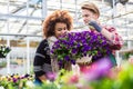 Beautiful woman thinking of buying a fragrant potted purple petunias