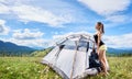 Woman tourist hiking in mountain trail, enjoying summer sunny morning in mountains near tent Royalty Free Stock Photo