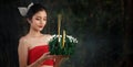 Beautiful woman in traditional Thai red dress holding krathong flower in her hands in loy krathong day concept Royalty Free Stock Photo