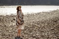 Beautiful woman traveler wearing hat and poncho walking at river beach, american outfit, boho concept, space for text Royalty Free Stock Photo