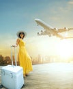 Beautiful woman and traveling luggage standing in airport terminal with passenger plane flying over sky