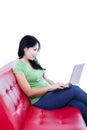 Beautiful woman typing on red sofa - isolated Royalty Free Stock Photo