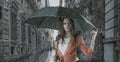 Beautiful woman with umbrella in town under rain