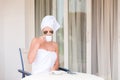 Beautiful woman in under eye patches with cup of coffee and towel on her head. Happy female on vacation enjoying fresh air in