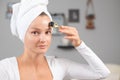 Beautiful woman is using anti aging derma roller. Woman is making needles procedure on face using meso roller Royalty Free Stock Photo