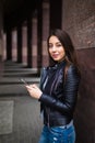 Beautiful young woman is using an app in her smartphone device to send a text message in front of a building background Royalty Free Stock Photo