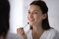 Beautiful woman using makeup brush applying concealer foundation cream