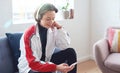 Beautiful woman using smartphone listening to music on mobile phone wearing headphones sitting on sofa at home Royalty Free Stock Photo