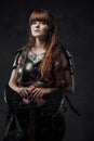 Beautiful woman viking with two handed axe in dark background