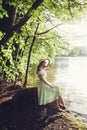 Beautiful woman in a vintage dress and hat sitting in park. Royalty Free Stock Photo