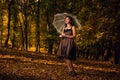 Beautiful woman in a vintage dress holding an umbrella standing in a park on a sunny autumn day Royalty Free Stock Photo