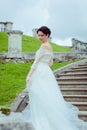 Beautiful woman in vintage wedding dress stay on stairs