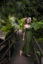 Beautiful woman walking across the bridge in tropical jungle. Caucasian woman wearing green dress. Nature and environment concept Royalty Free Stock Photo
